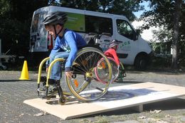 Kind probiert das Rollstuhlfahren über eine Wippe aus