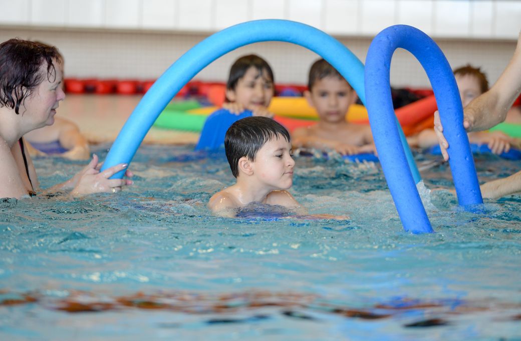 Kind schwimmt durch Nudel-Bogen