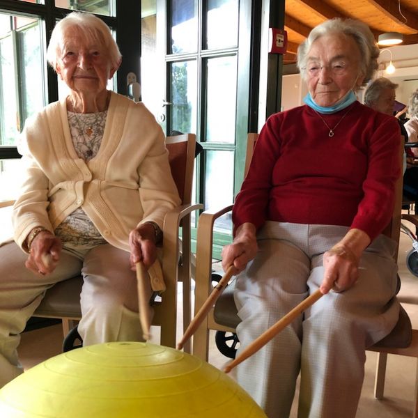 Seniorinnen mit Drum-Sticks, die auf einen Gymnastikball schlagen