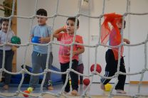 Kinder werfen mit bunten Bällen durch das Kletternetz